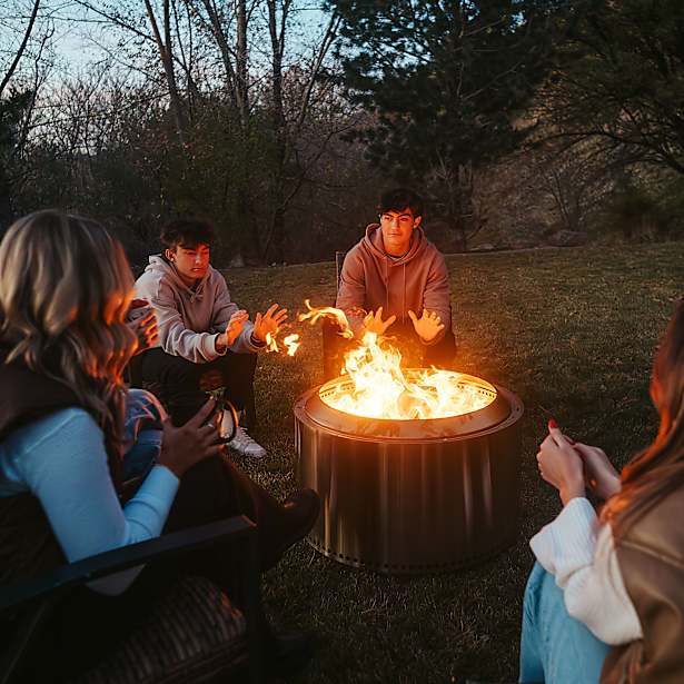 People sitting around a fire pit in a natural setting