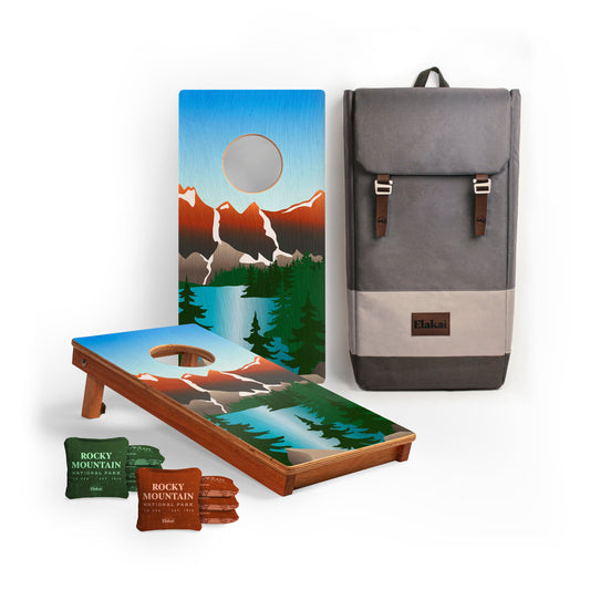 Cornhole board with mountain design, cornhole bags, and a backpack. Rocky Mountain National Park.